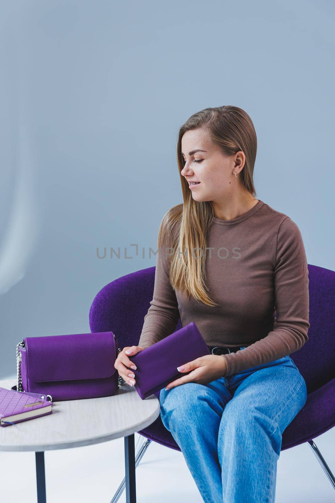 A purple leather bag in a girl's hand. Woman with luxury bag.
