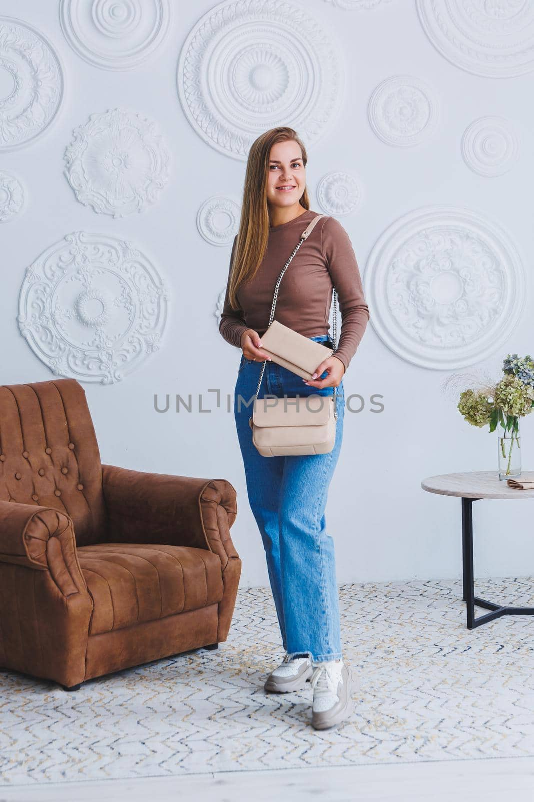 Stylish look. Close-up of beige handbag in hands. Fashionable girl. Close-up photo of a girl with a handbag in her hands.