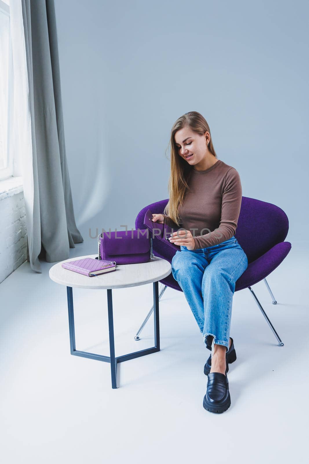 A purple leather bag in a girl's hand. Woman with luxury bag.