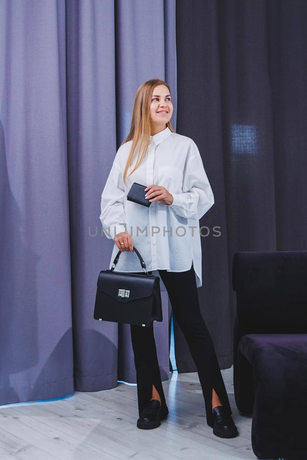 Black classic leather bag in a girl's hand. Woman with luxury bag.