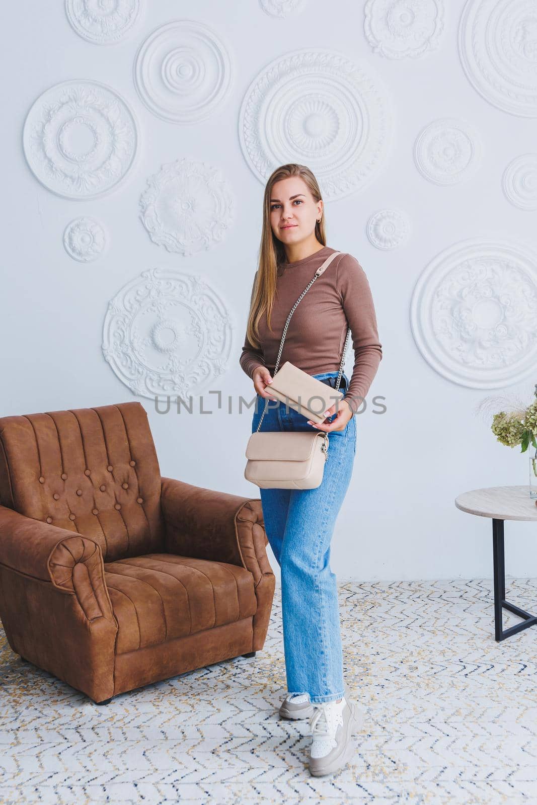 Stylish look. Close-up of beige handbag in hands. Fashionable girl. Close-up photo of a girl with a handbag in her hands.