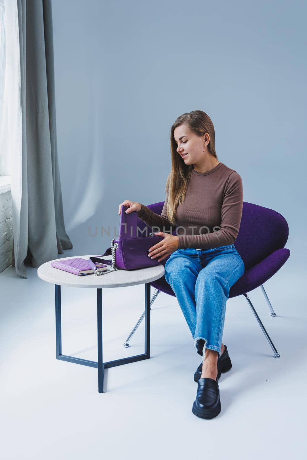 A purple leather bag in a girl's hand. Woman with luxury bag.