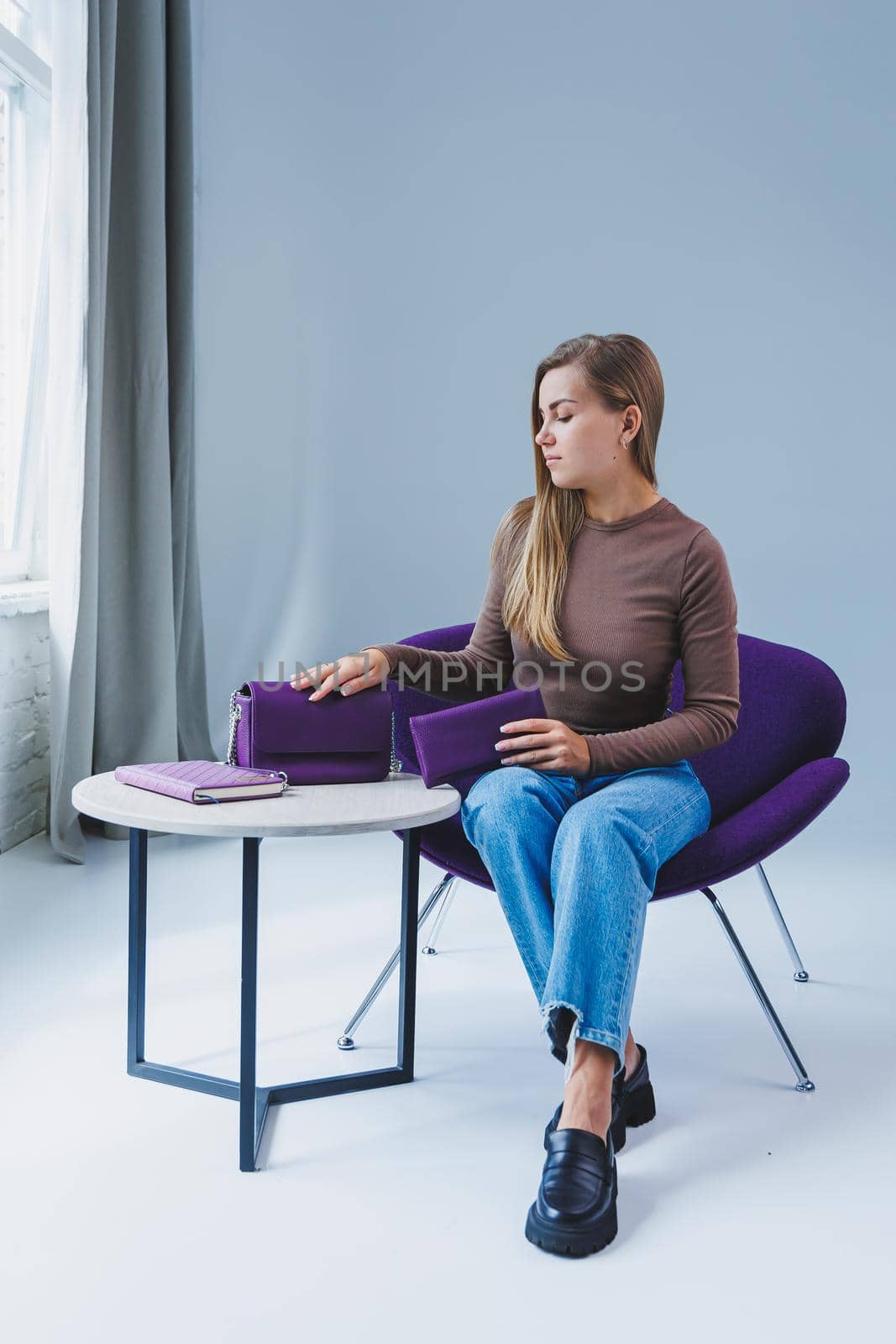 A purple leather bag in a girl's hand. Woman with luxury bag.
