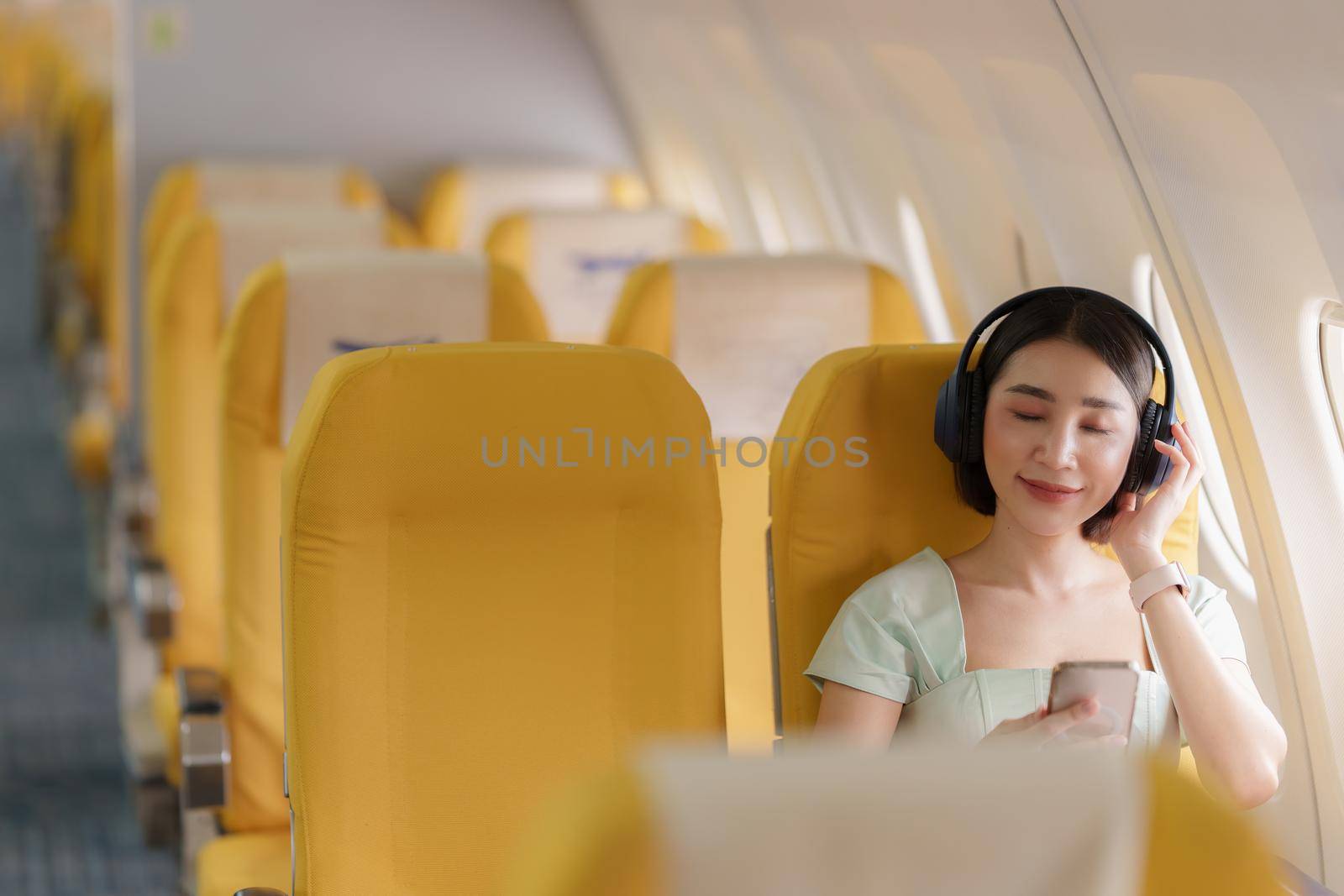 Young asian woman using smartphone connected to wifi internet during flight on board. Travel concept by itchaznong