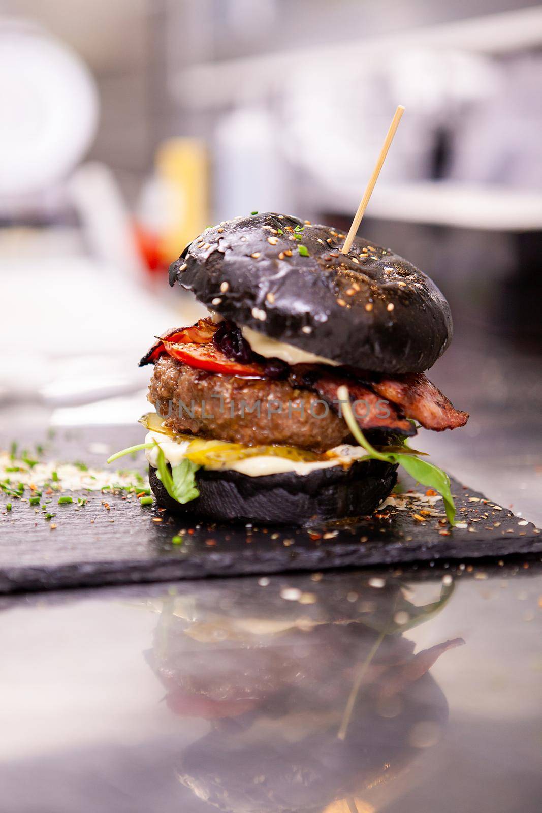 Black burger on stone cutting board in kitchen restaurant