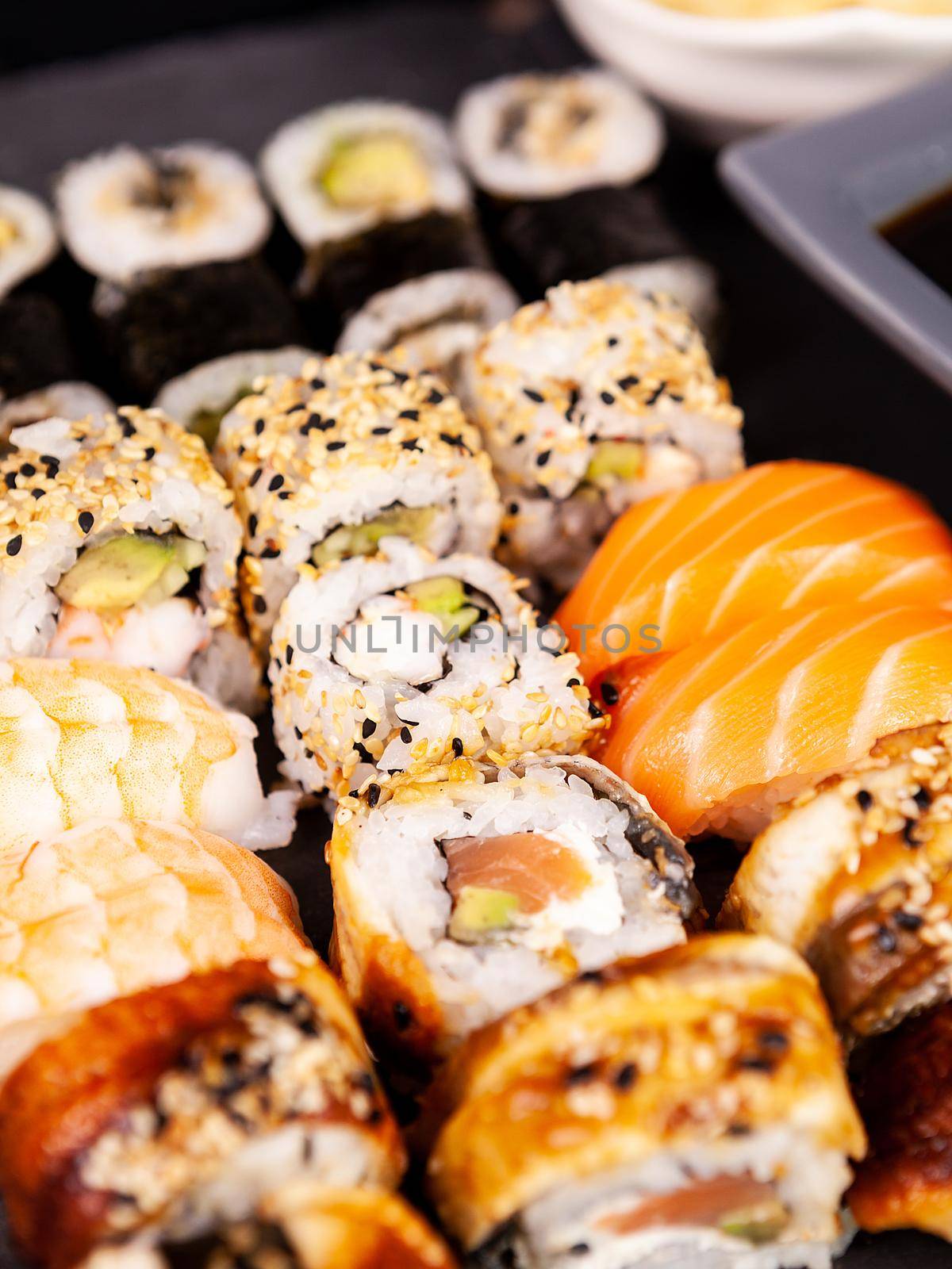 Lot mix variety of sushi rolls on black stone background in studio photo