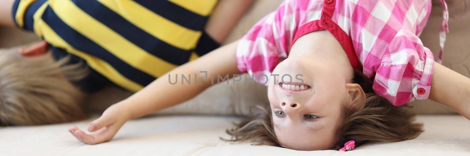 Children have fun at home, kids upside down on sofa, holiday at school by kuprevich