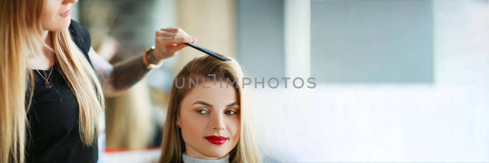 Portrait of hairdresser using comb to brush clients hair, woman on appointment in salon. Professional master in beauty center. Wellness, barbershop concept