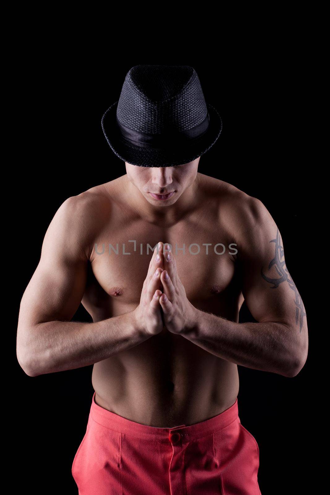 Portrait of muscular dancer in hat in dark
