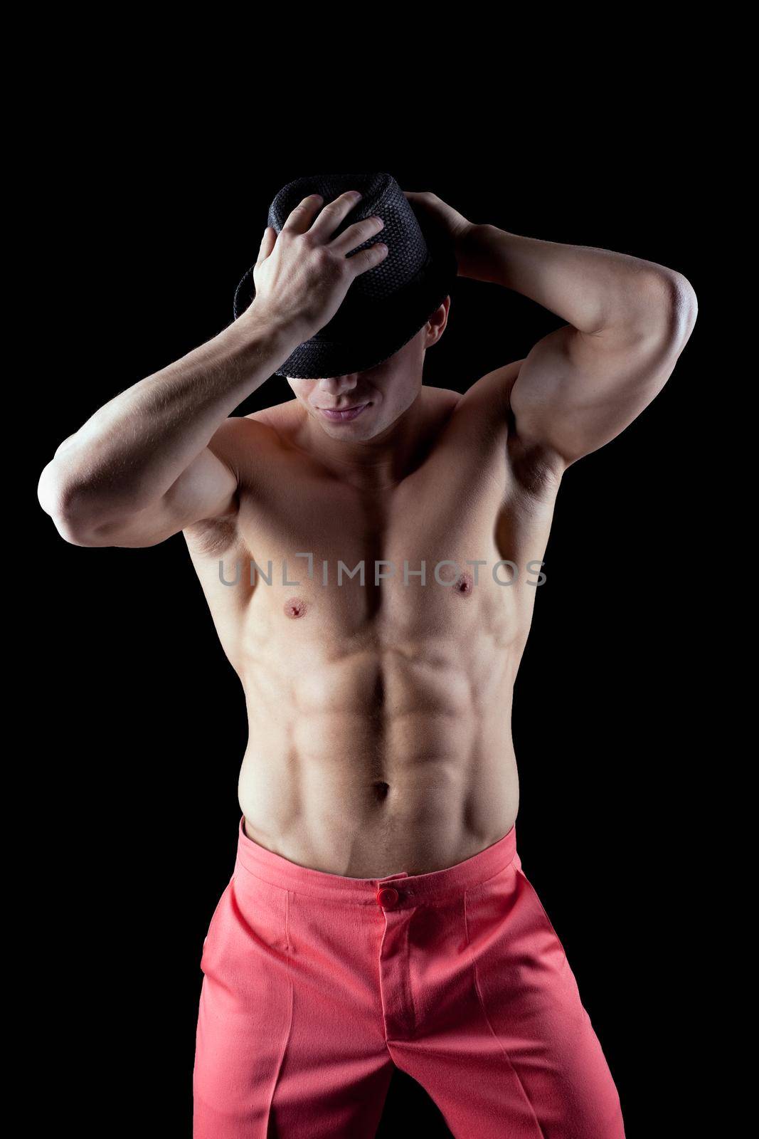 athletic man show striptease in dark with hat