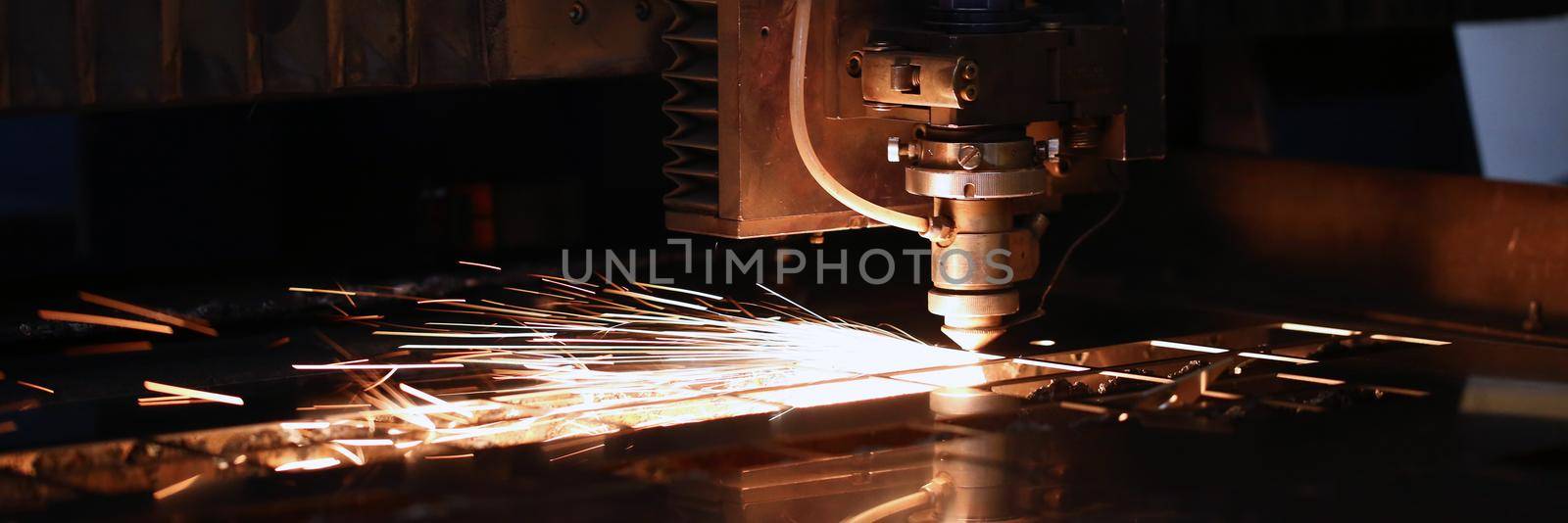 Close-up of sparks fly out of automated machine, metal processing laser on metallurgical background. Manufacturing, parts for automotive production concept