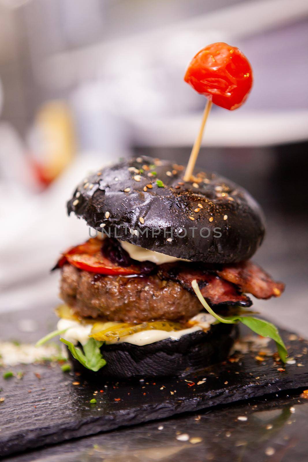 Black burger on stone cutting board in kitchen restaurant