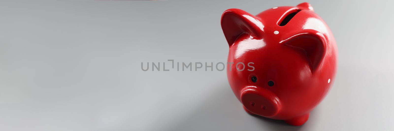 Bright red piggybank container on grey surface, empty thing to put money by kuprevich