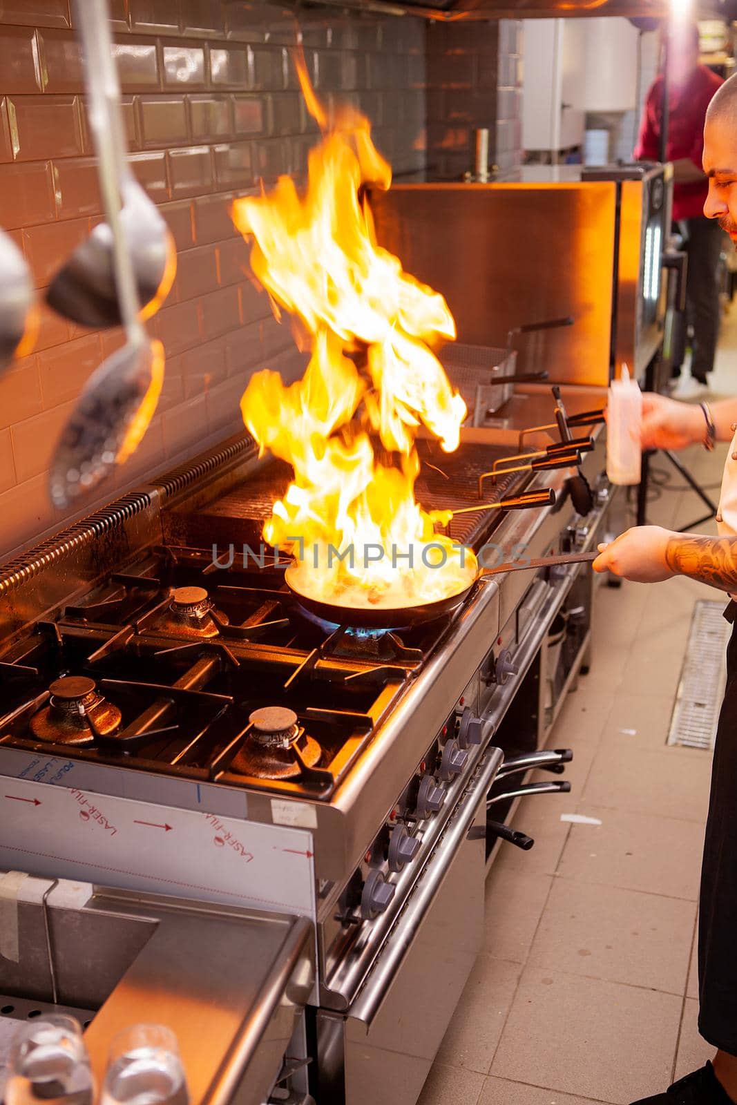 The chef prepares the dish on the stove with an open fire in the kitchen of the restaurant.