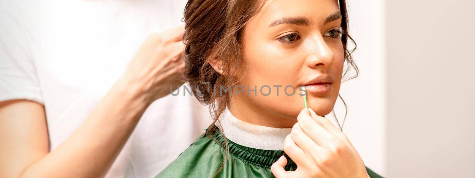 Makeup artist and hairdresser prepare the bride making hairstyle and makeup in a beauty salon