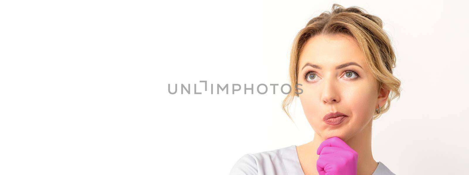 Young caucasian female doctor wearing gloves thoughtful looking away isolated on white background