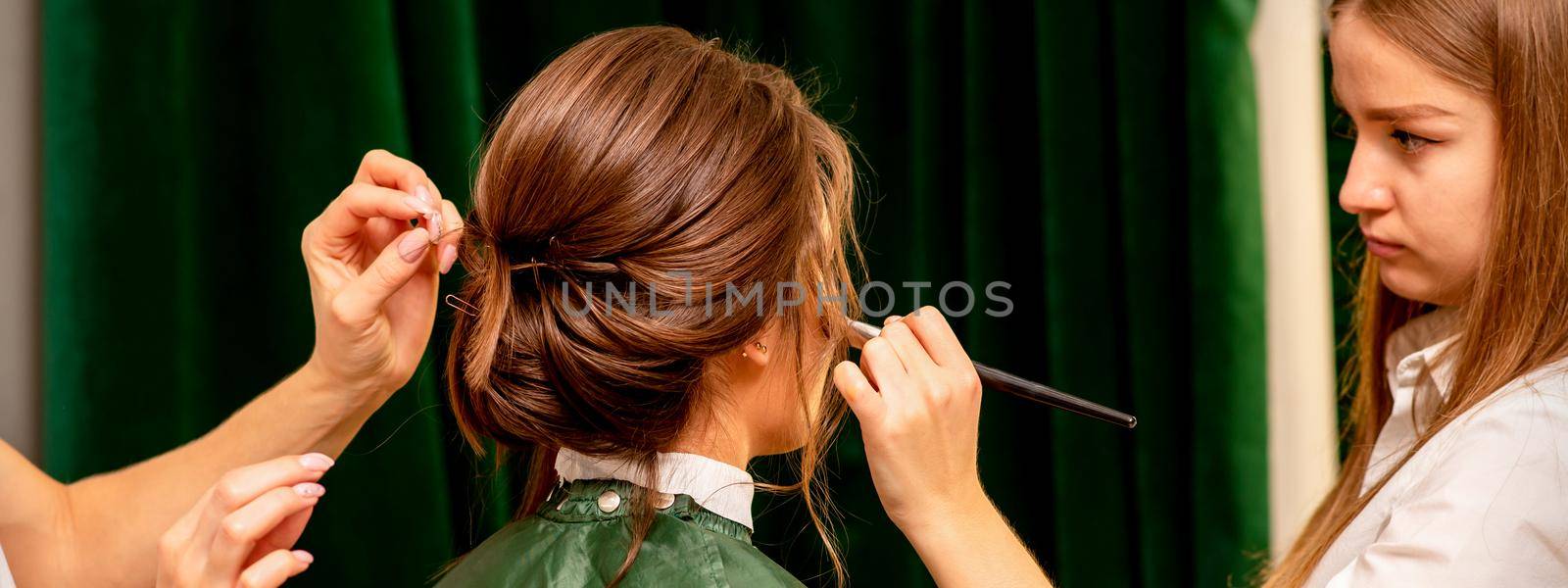 Makeup artist and hairdresser prepare the bride making hairstyle and makeup in a beauty salon