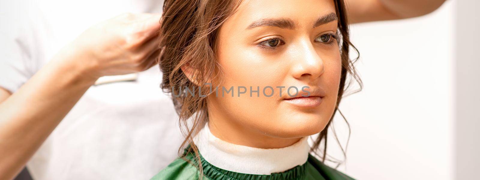 Hairstyling bride. A female hairdresser makes styling hair for the beautiful young caucasian woman in a beauty salon