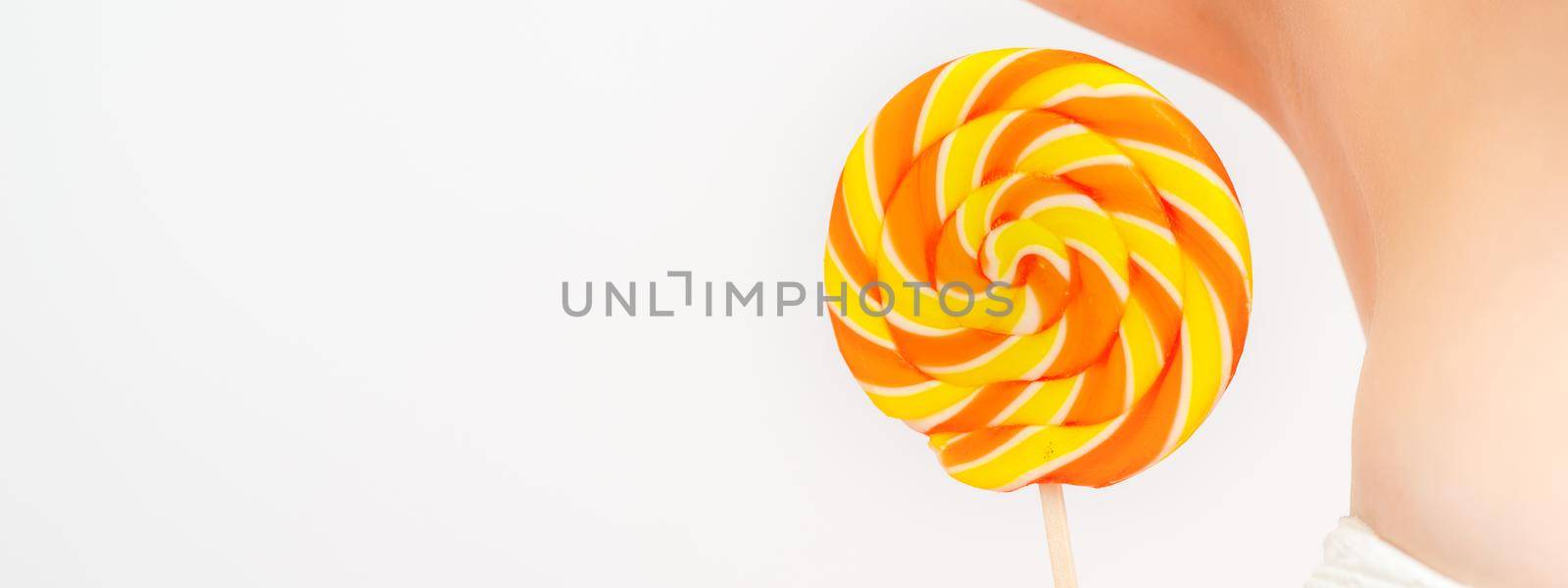 Waxing, depilation concept. A young female holds a round lollipop near her armpit on white background