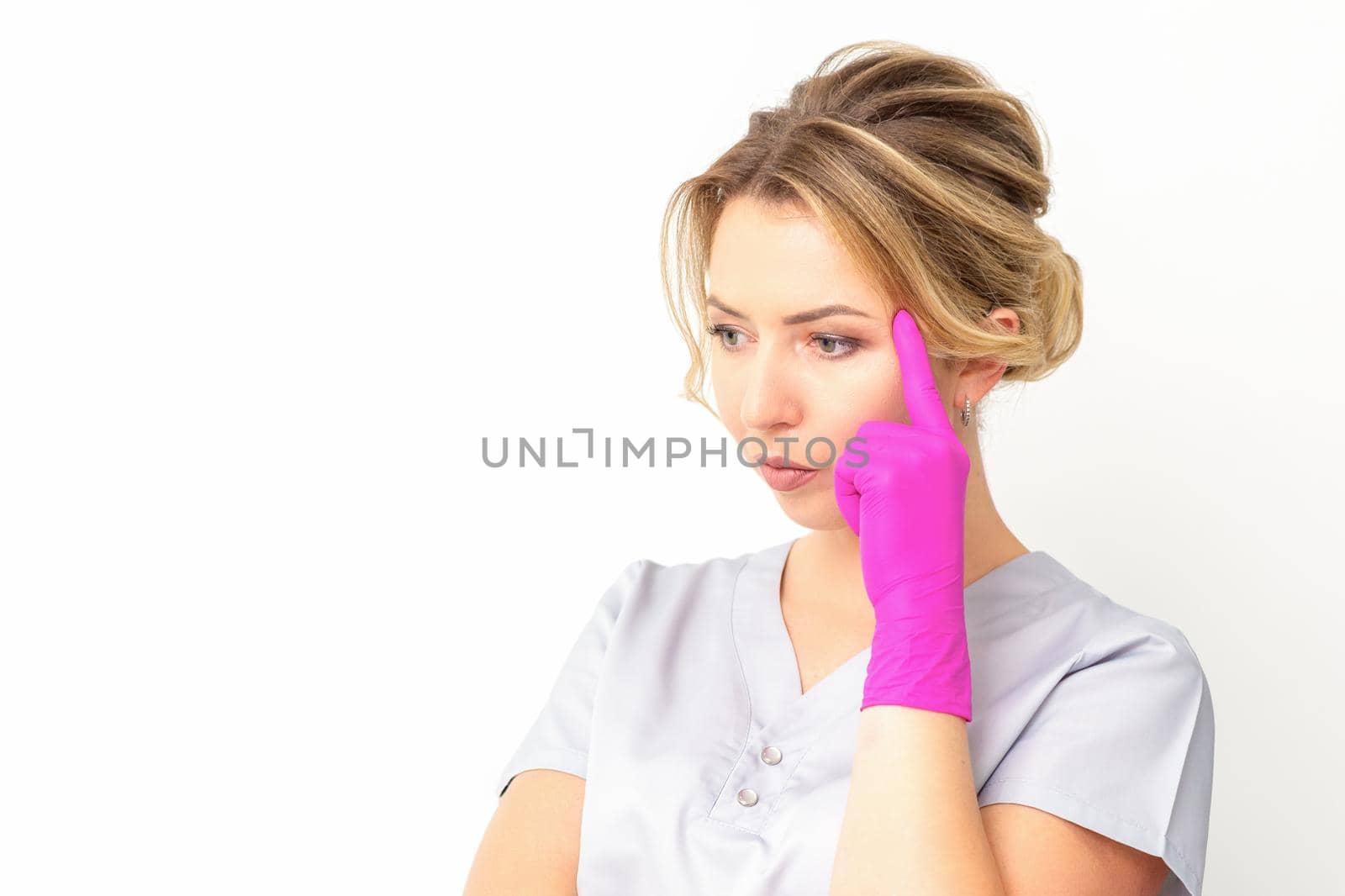 Young caucasian female doctor wearing gloves thoughtful looking away isolated on white background