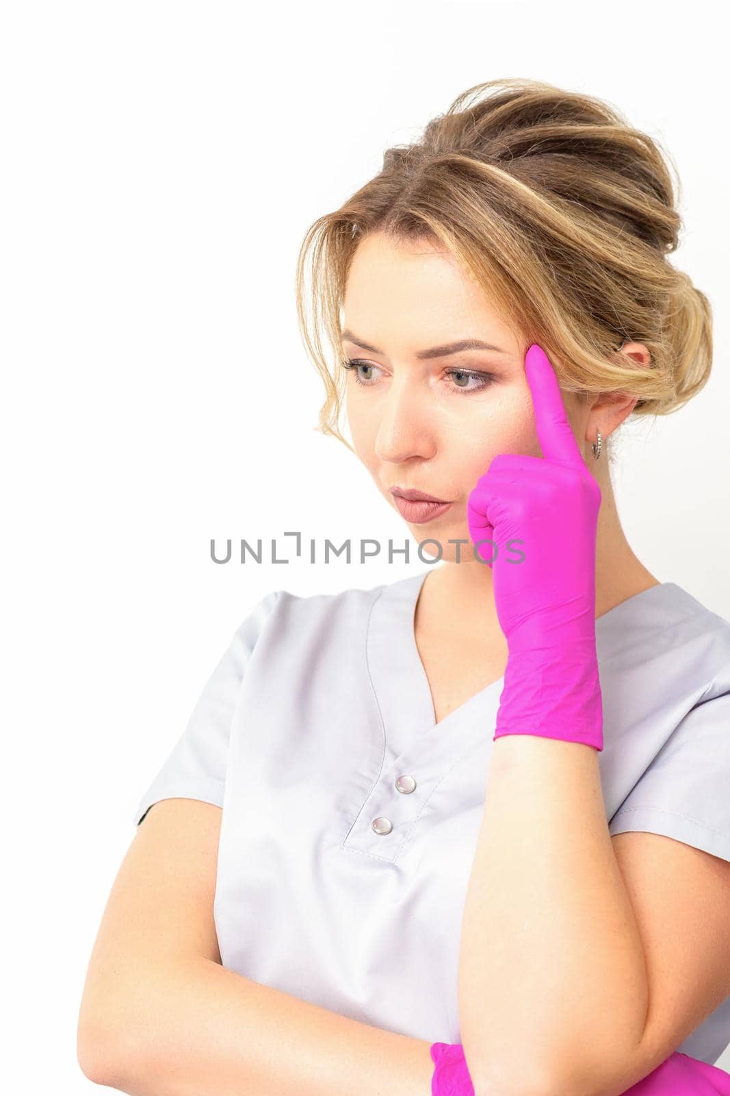 Young caucasian female doctor wearing gloves thoughtful looking away isolated on white background