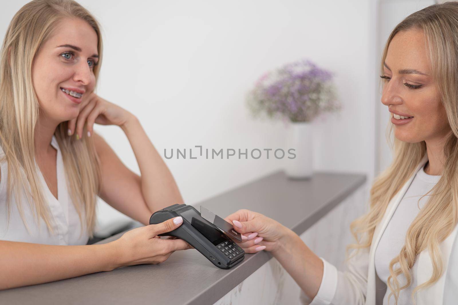 A young woman pays in a beauty salon with a credit card using NFC contactless payment