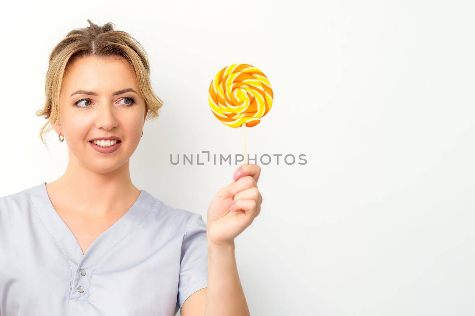 Waxing, depilation concept. The beautician is wearing a medical coat holding a sugar lollipop on white background