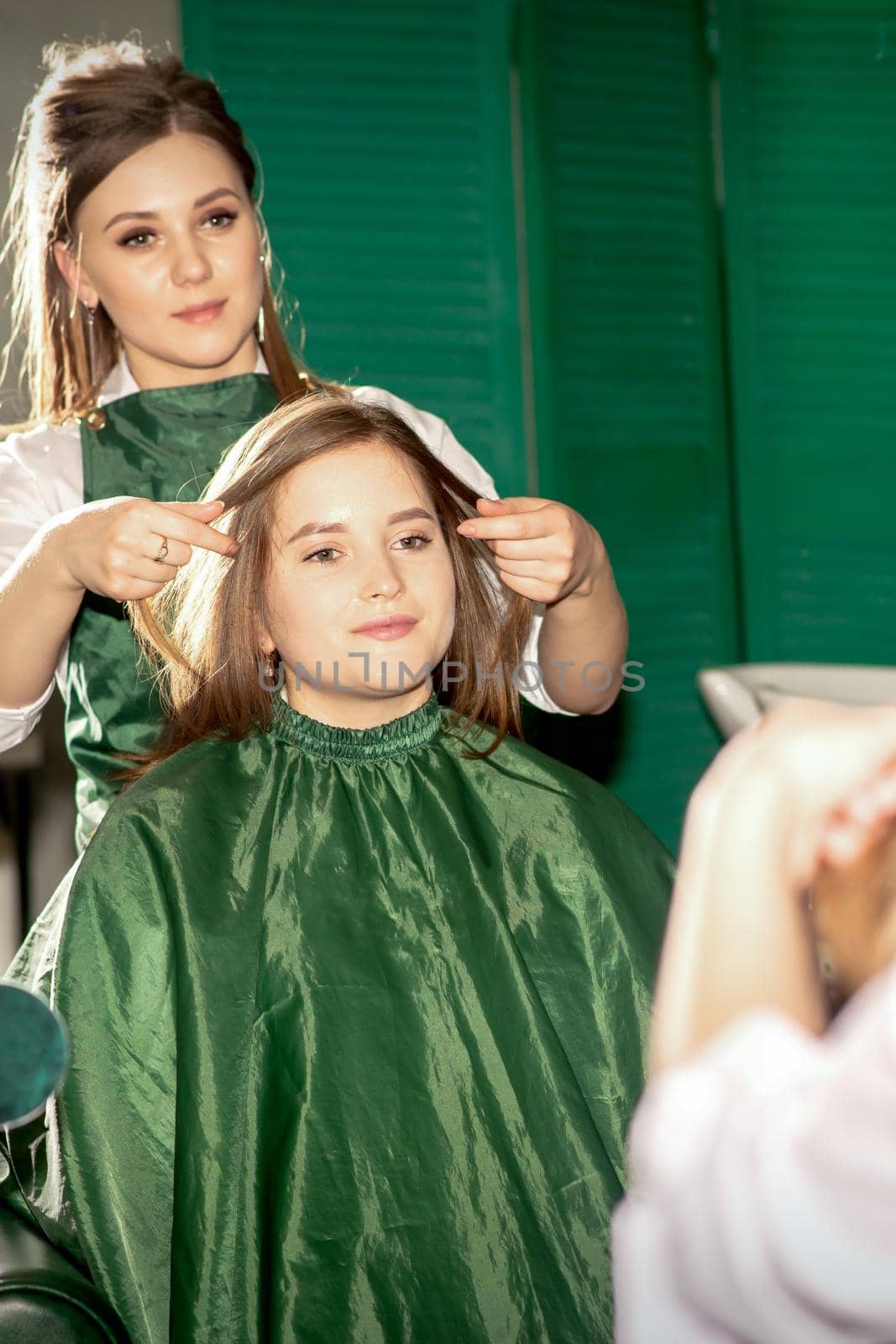 Professional hair care. Beautiful young caucasian brunette woman with long hair receiving hairstyling in a beauty salon