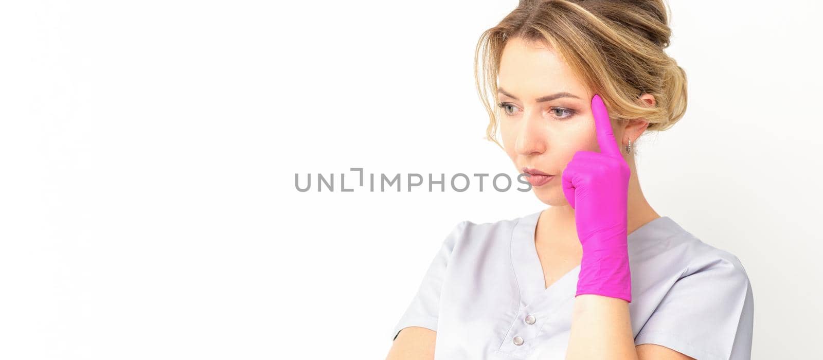 Young caucasian female doctor wearing gloves thoughtful looking away isolated on white background