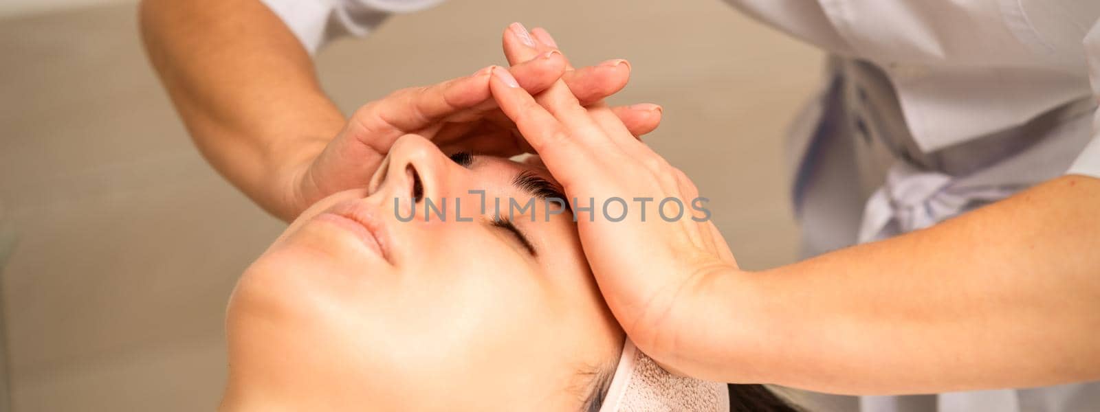 Facial massage. Young caucasian woman with closed eyes getting a massage on her forehead in a beauty salon