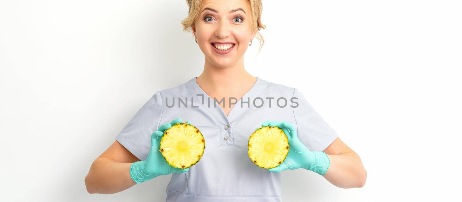 Young Caucasian smiling woman doctor nutritionist holding slices pineapple over isolated white background, breast health concept