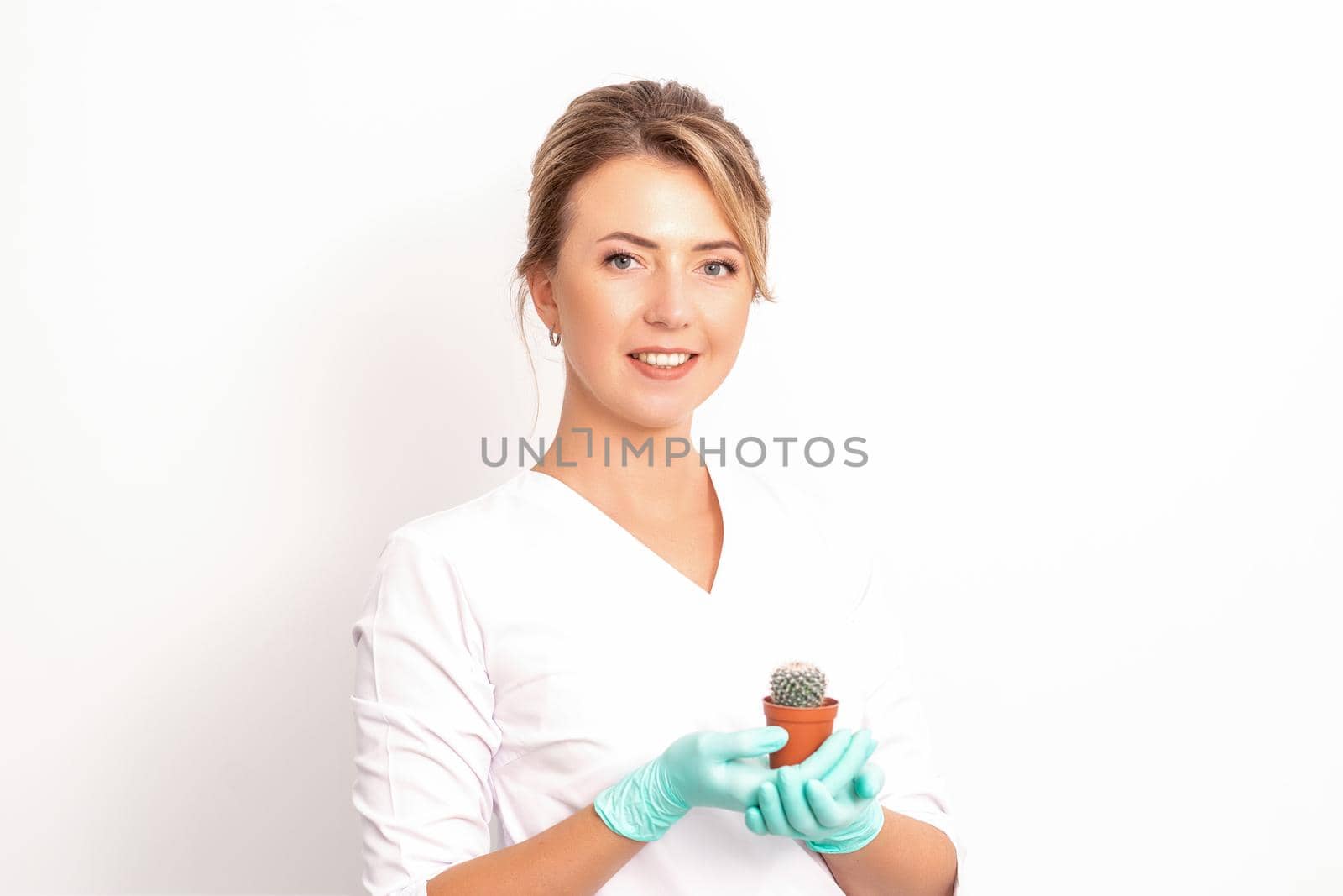 A portrait of a smiling female holds little green cactus in her hands. Hair removal concept