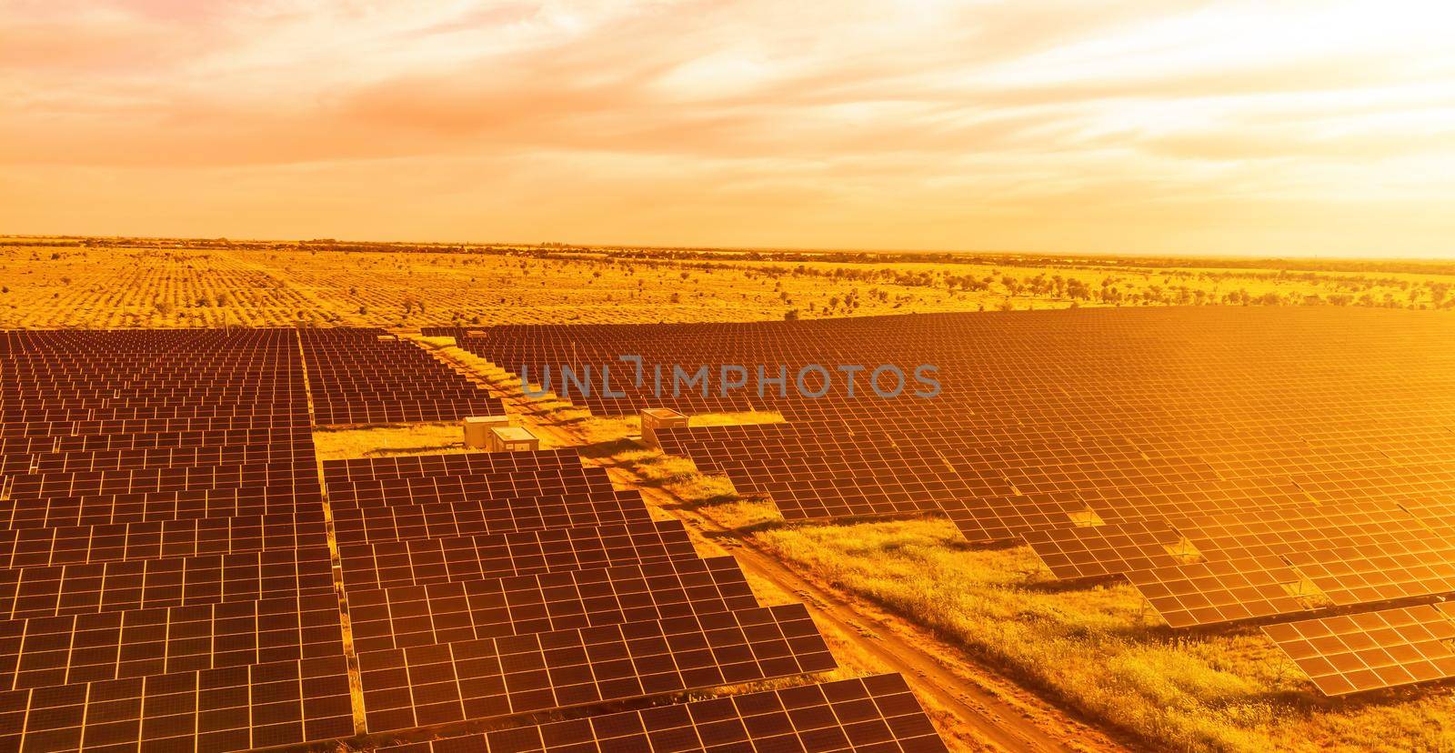 Aerial top view of a solar panels power plant. Photovoltaic solar panels at sunrise and sunset in countryside from above. Modern technology, climate care, earth saving, renewable energy concept. by panophotograph