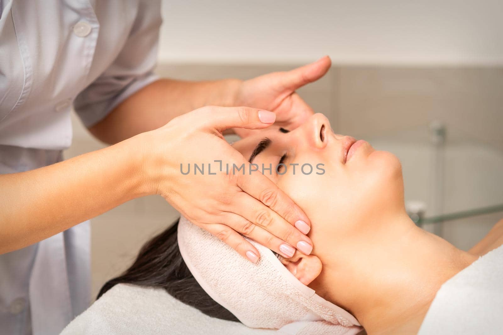 Young caucasian woman with closed eyes getting a facial massage in a beauty clinic