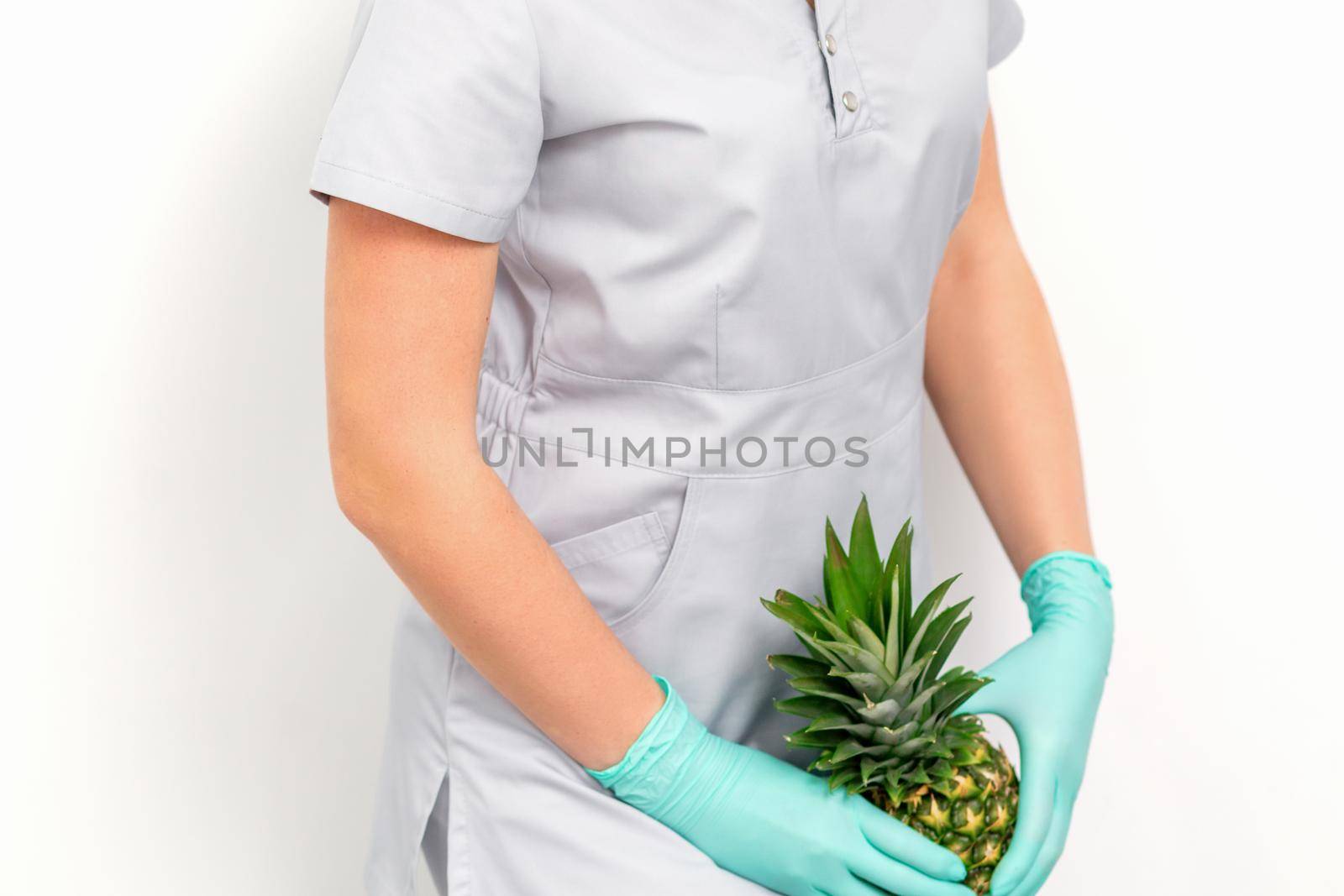 Female doctor beautician with pineapple. Concept of epilation or depilation and intimate hygiene