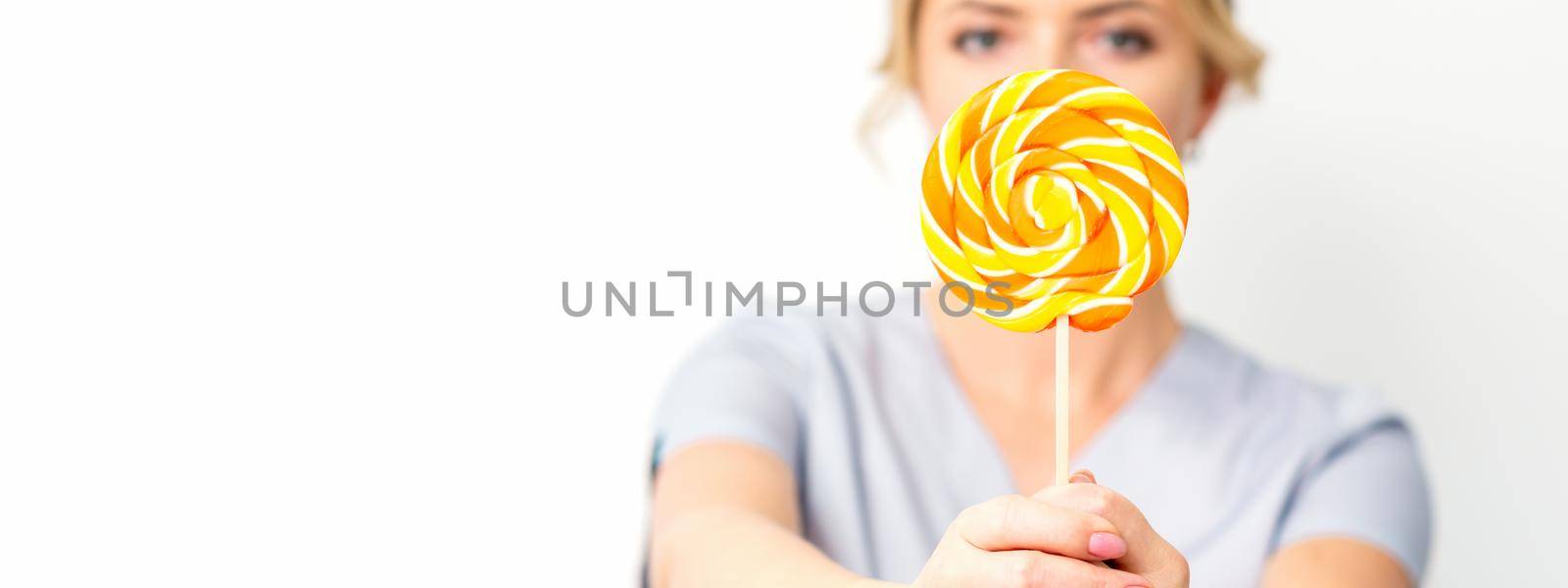 Waxing, depilation concept. The beautician is wearing a medical coat holding a sugar lollipop on white background