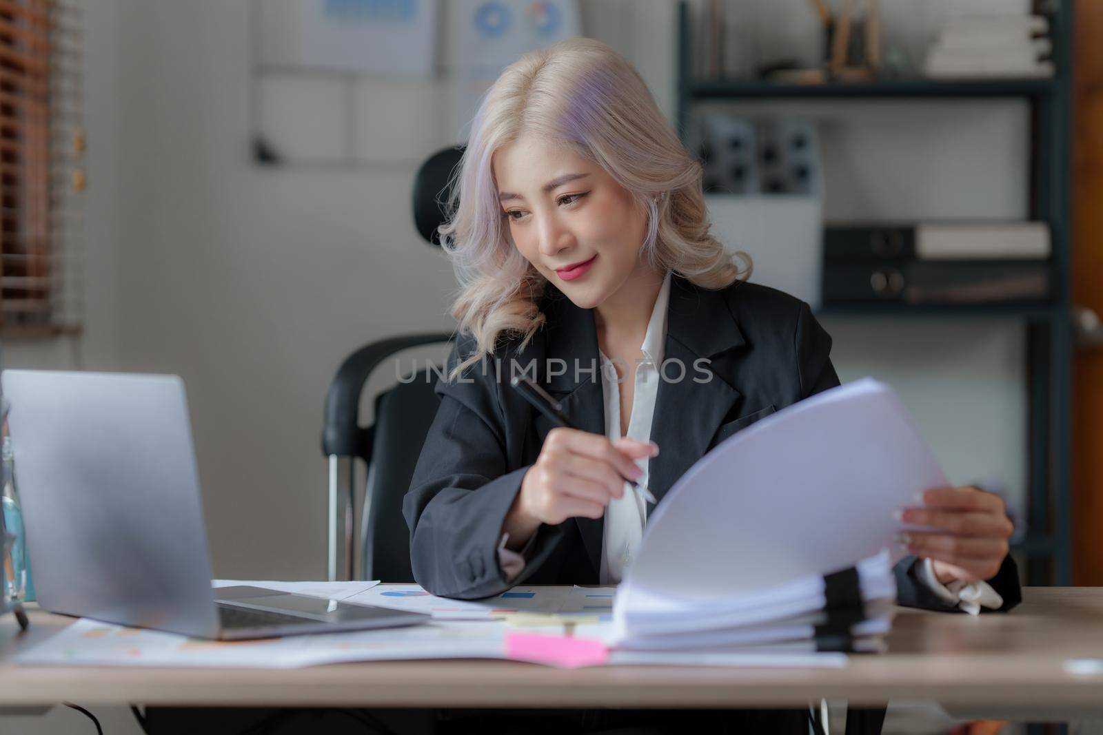 Beautiful Asian businesswoman analyzes financial charts. Account and audit concept by itchaznong
