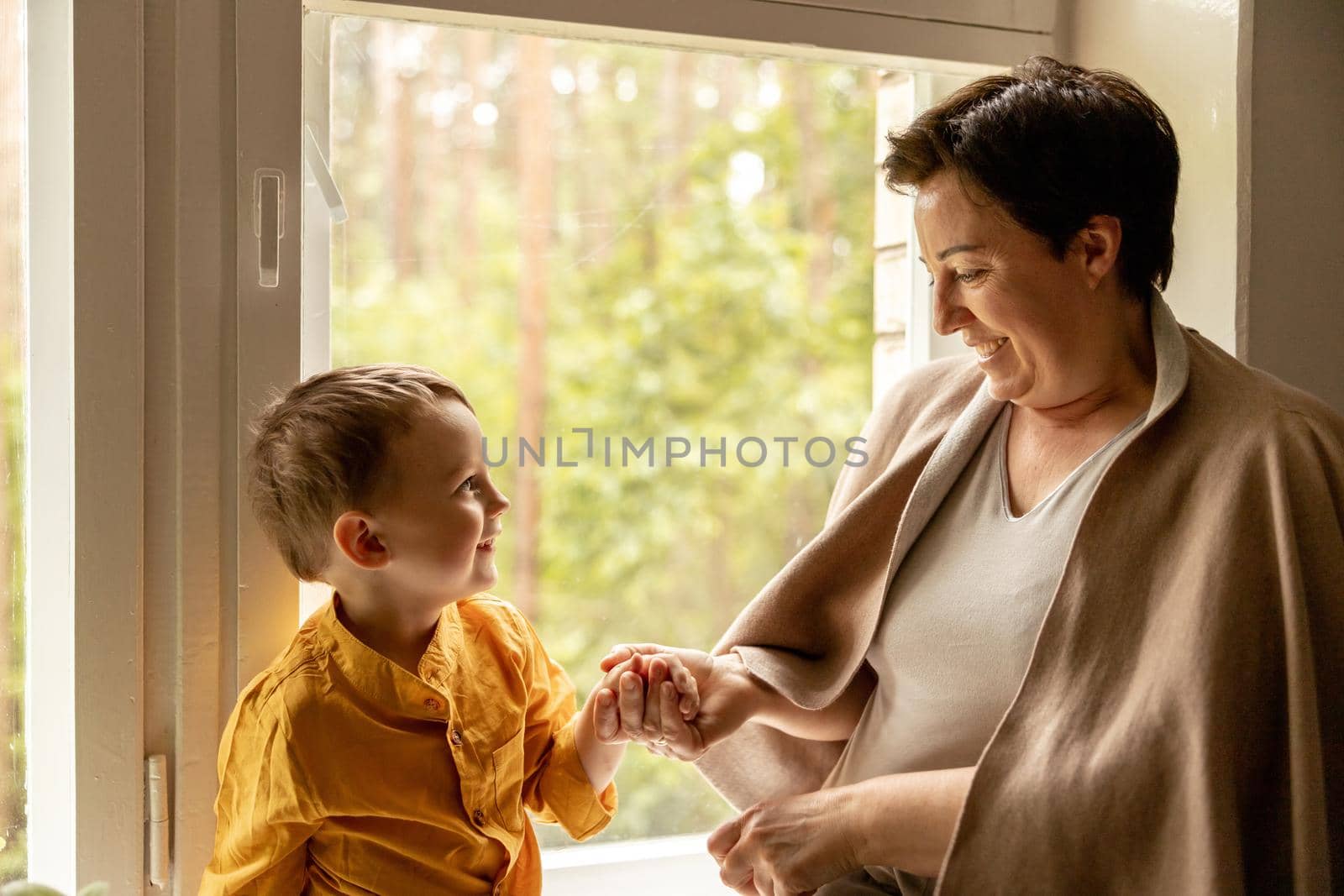 Happy grandmother and grandson enjoy time together. Positive middle age woman spending time with little, cute grandchild. 50-year-old grandma with grandkid. Multi-generational family