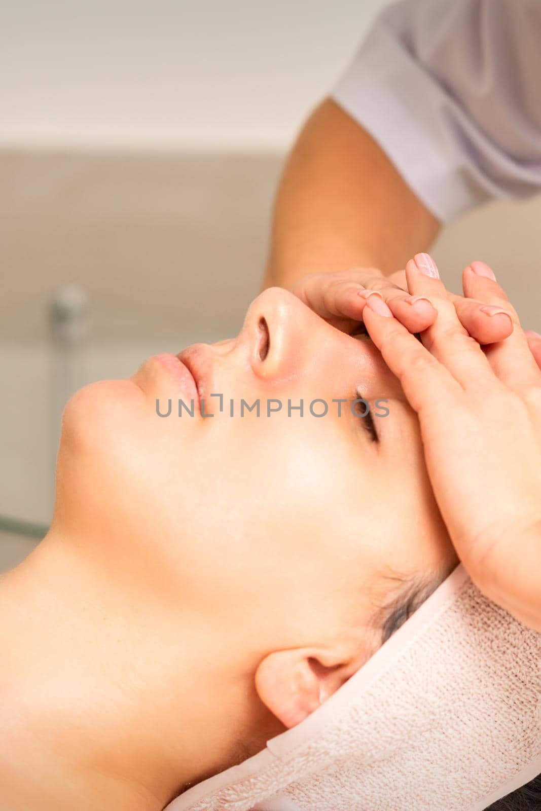 Facial massage. Young caucasian woman with closed eyes getting a massage on her forehead in a beauty salon