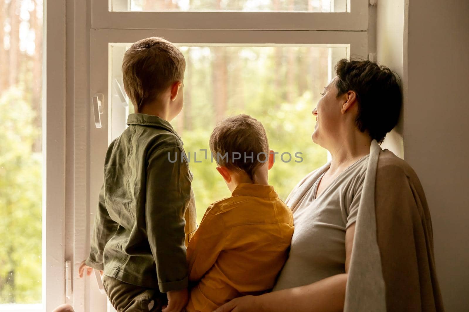 Happy grandmother and her grandsons enjoy time together. Positive middle age woman spending time with little, cute grandchildren. 50-year-old grandma with grandkids. Multi-generational family