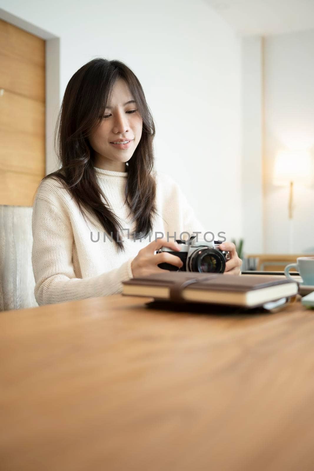 Young female photographer holding camera while sitting in her office room. by prathanchorruangsak