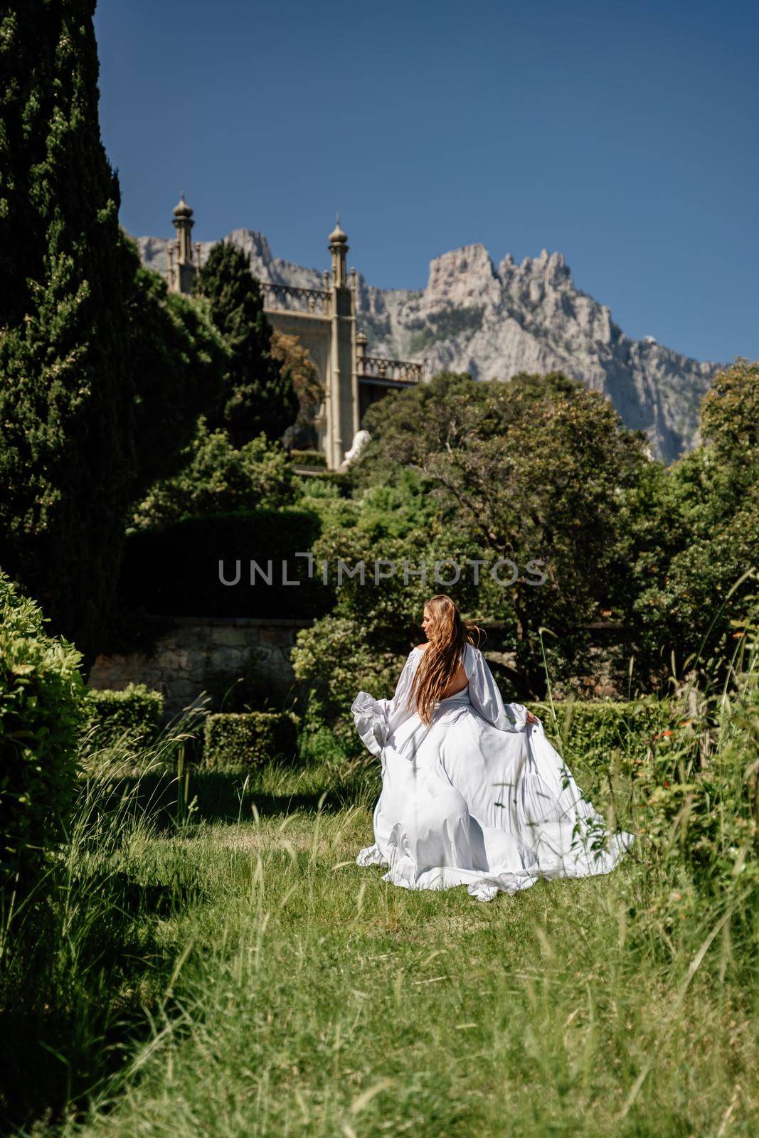 a beautiful woman with long brown hair stay along a path along beautiful bushes in the park