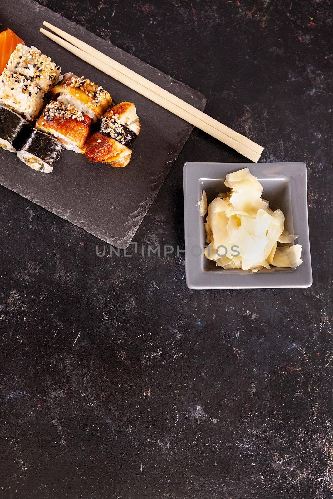 Sushi plate on dark stone next to ginger on black background with copyspace available