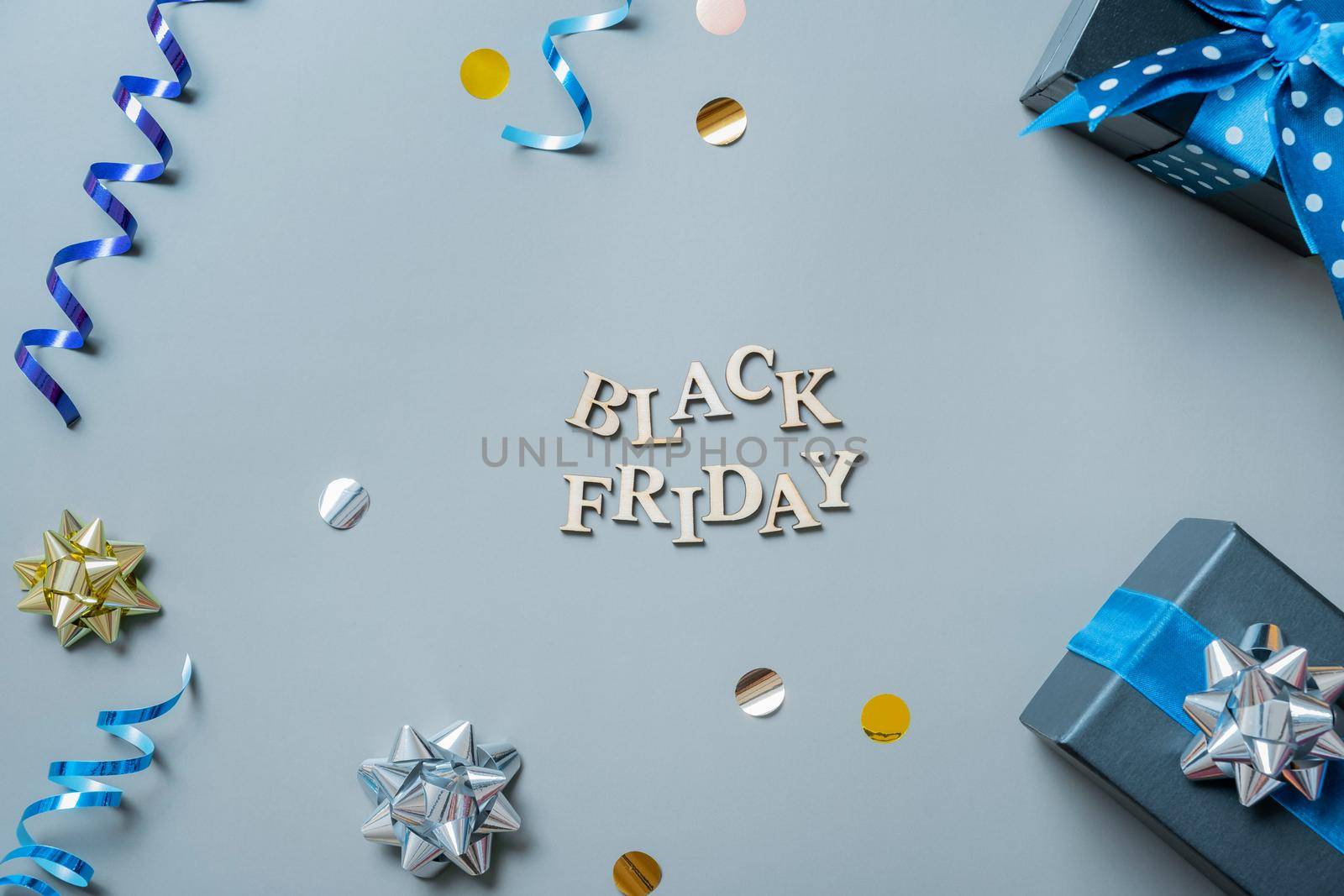 Black friday text with gifts and festive tinsel flat lay.
