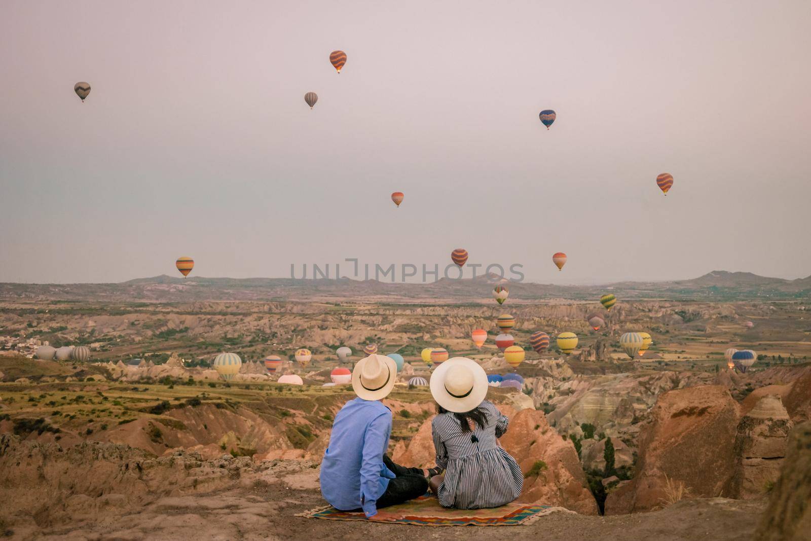 Kapadokya Cappadocia Turkey, a happy young couple during sunrise watching the hot air balloons of Kapadokya Cappadocia Turkey during vacation. Asian women and caucasian men on holiday in Turkey