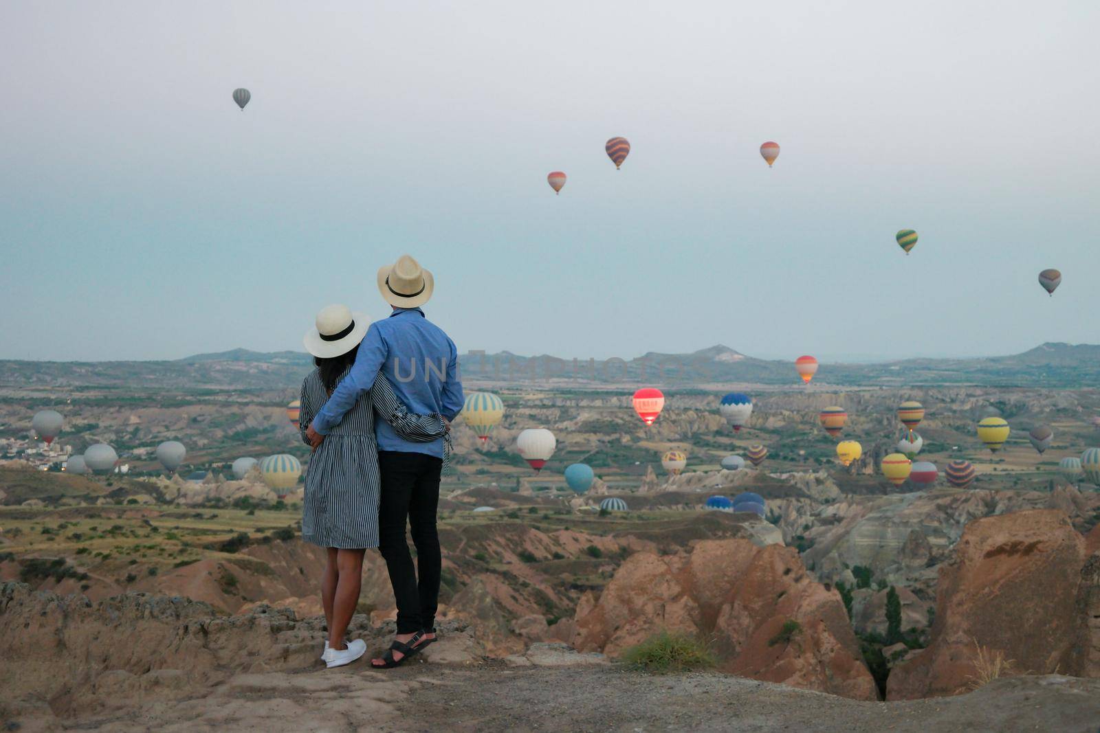 happy young couple during sunrise watching the hot air balloons of Kapadokya Cappadocia Turkey by fokkebok