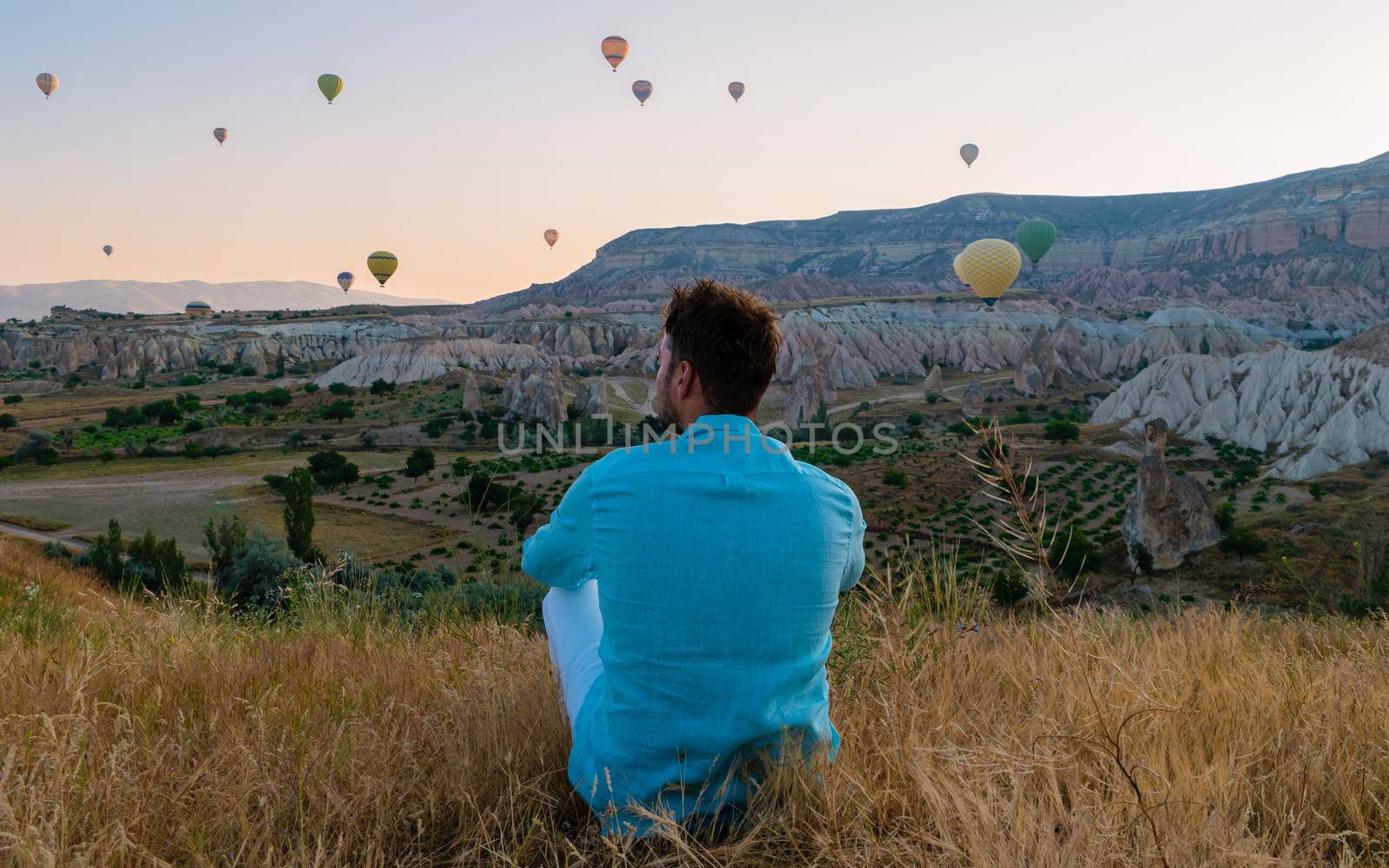 Young men watching hot air balloon during sunrise in Cappadocia Turkey, Kapadokya Goreme by fokkebok