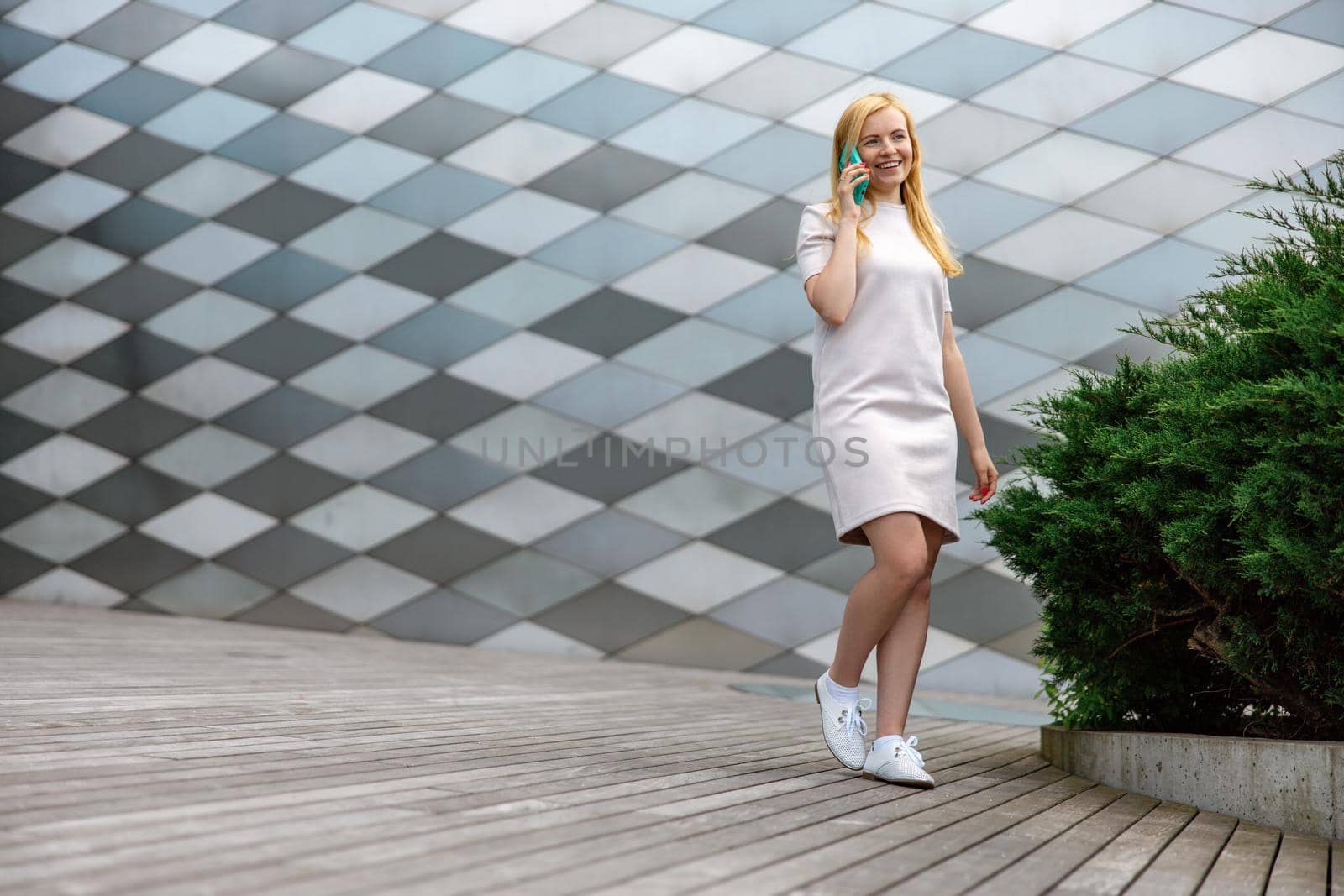 Young blond woman making a call with her smartphone. Girl talking with friends with mobile phone. Leisure activity, communication. Conversation. Mobile technology. by creativebird