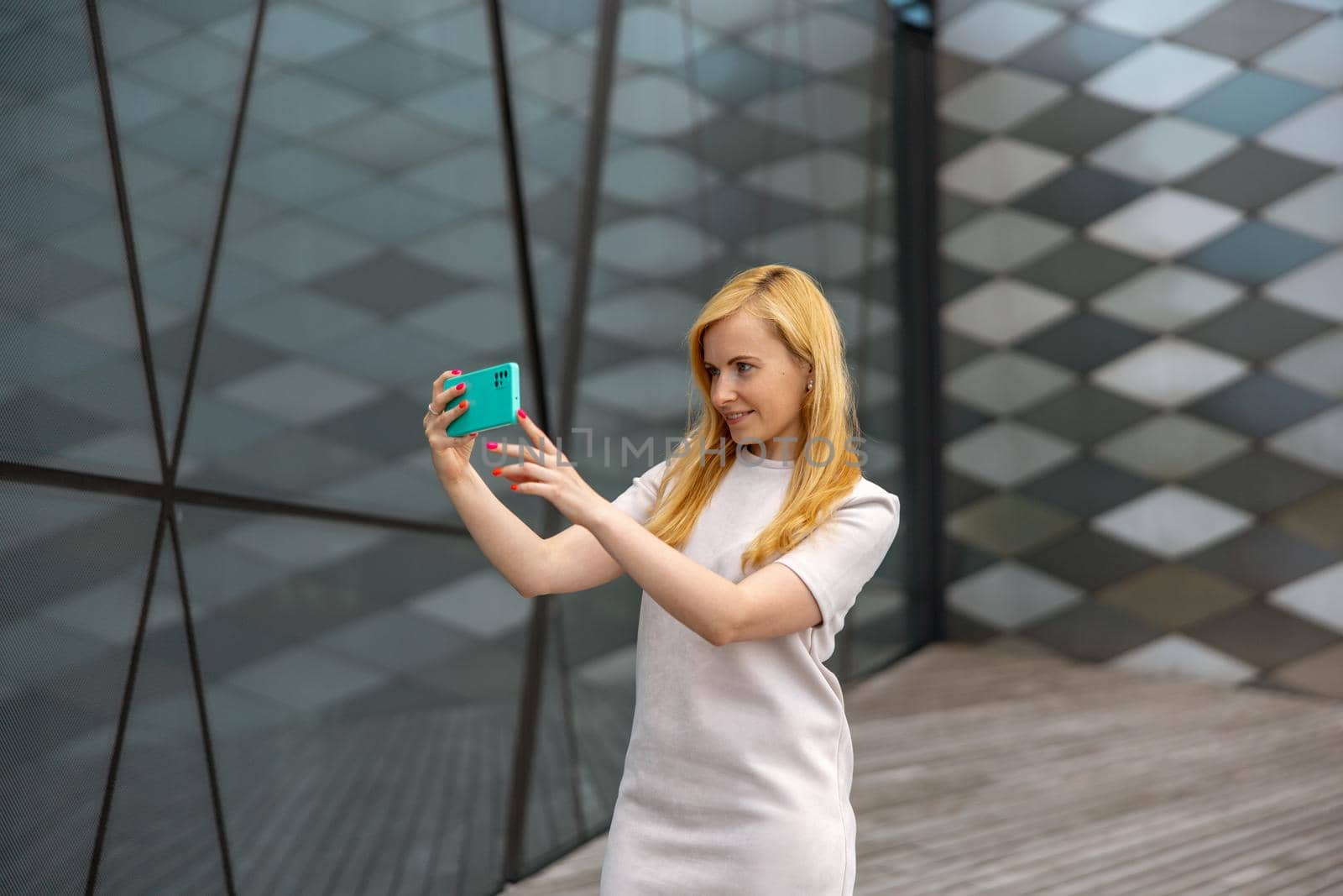 Young blond woman making selfie on smartphone for her followers. Young influencer girl. Popularity in internet, friends online. Beautiful girl making content for her social media account. by creativebird
