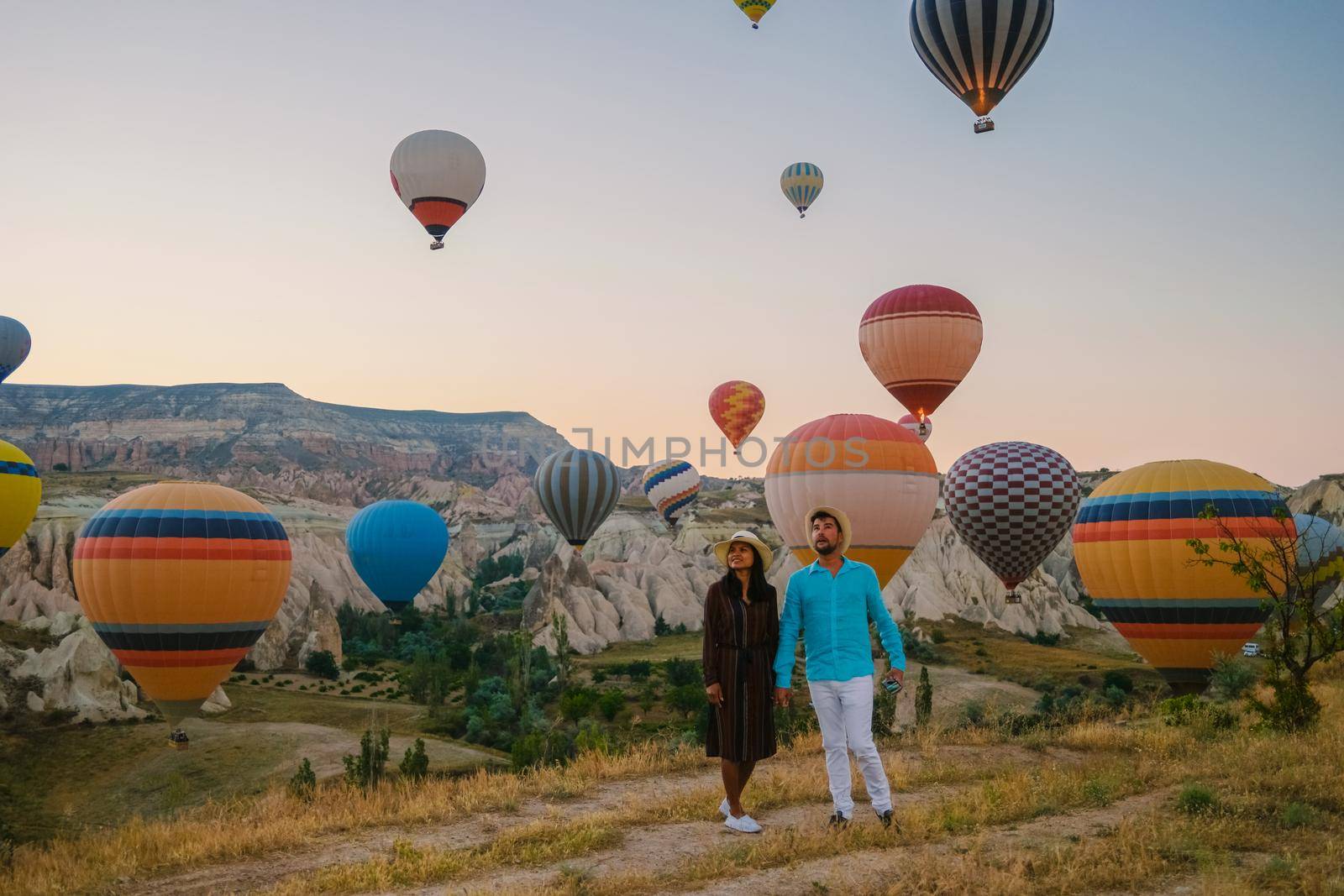 happy young couple during sunrise watching the hot air balloons of Kapadokya Cappadocia Turkey by fokkebok